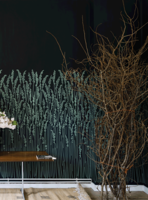 壁：FARROW&BALL 壁紙 5106 Feather Grass / 夜空を思わせるようなダークカラーのベースに、月の光に照らされたような青白いススキが描かれている壁紙が貼られた空間。前に枝のディスプレイと木製のベンチが置かれている。