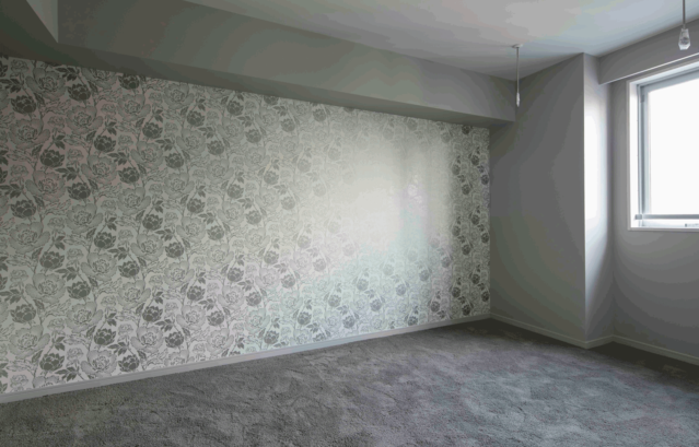 壁：FARROW&BALL 壁紙 2303 Peony / マンションのリフォームされた部屋。グレーのカーペットに合わせて、アクセントウォールには大柄のシルバーの花が施された壁紙が貼られている。