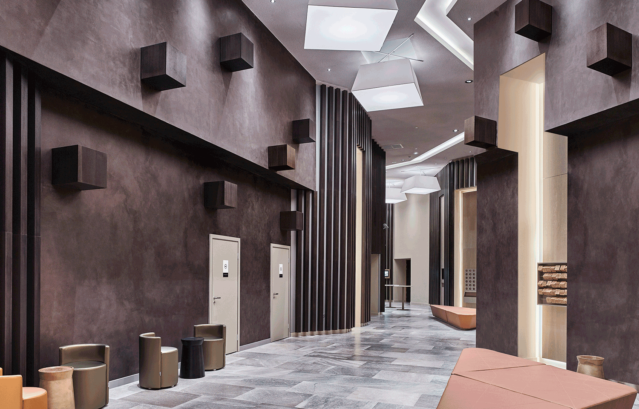 （壁）VALPAINT：Klondike / 鈍い金や銀、酸化した鉄材のようなメタリックな質感を表現できるKlondikeが塗装された空間。鈍い赤茶系のKlondikeで塗装されたホールは重厚感を感じさせる。明るいグレー系の床と天井が抜け感を作っており、峡谷の間をあるくような特別な雰囲気をインテリアにもたらしている。