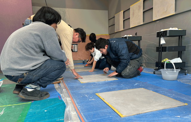 カラーワークスファクトリーで開催されている、MPCテクニカル講習の様子。受講生のプロの方が、床への施工を講師から学んでいる様子。