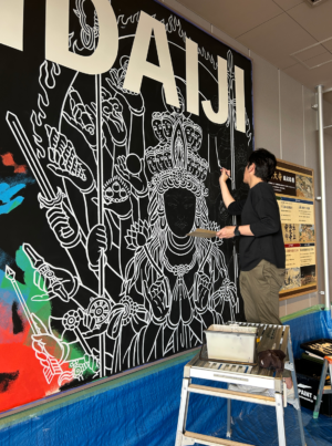 黒地に白い線で描かれた壁画の前で、作業を進める2人